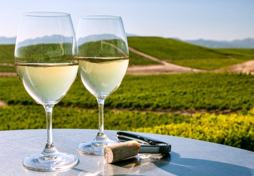 Two white wine glasses at a table overlooking the Sonoma County, in California.